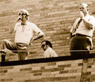 Band directors oversee the marching band from the roof of the school auditorium